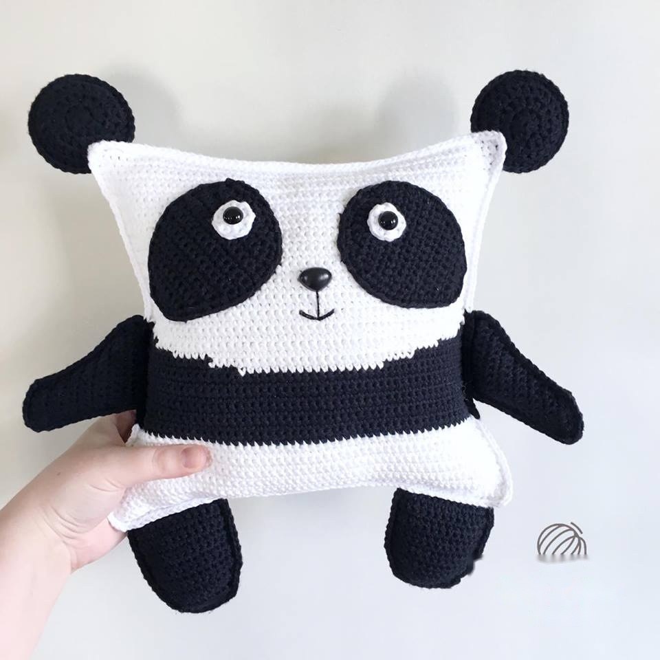 Finished crochet pudgy panda plushie in black and white yarn on neutral table