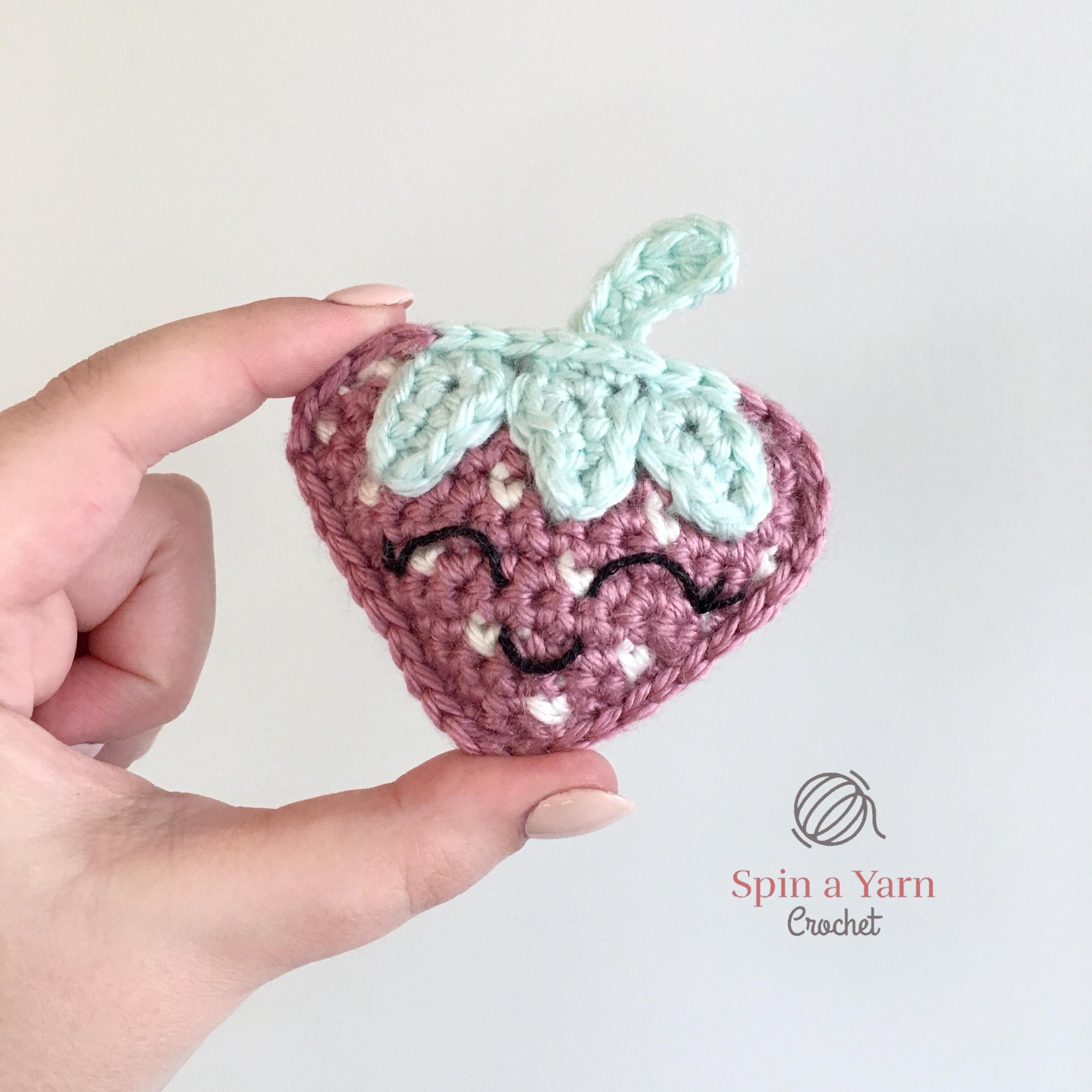 Crochet strawberry between fingers