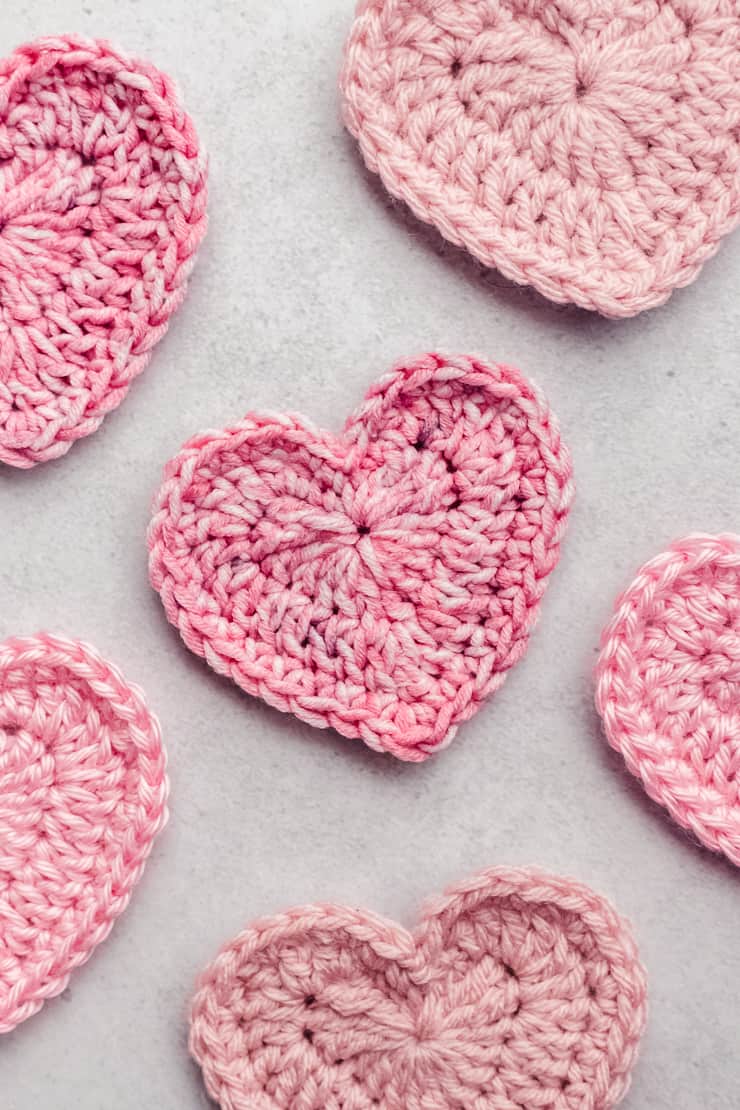 Trio of pink and red crochet hearts in 3 sizes on light background