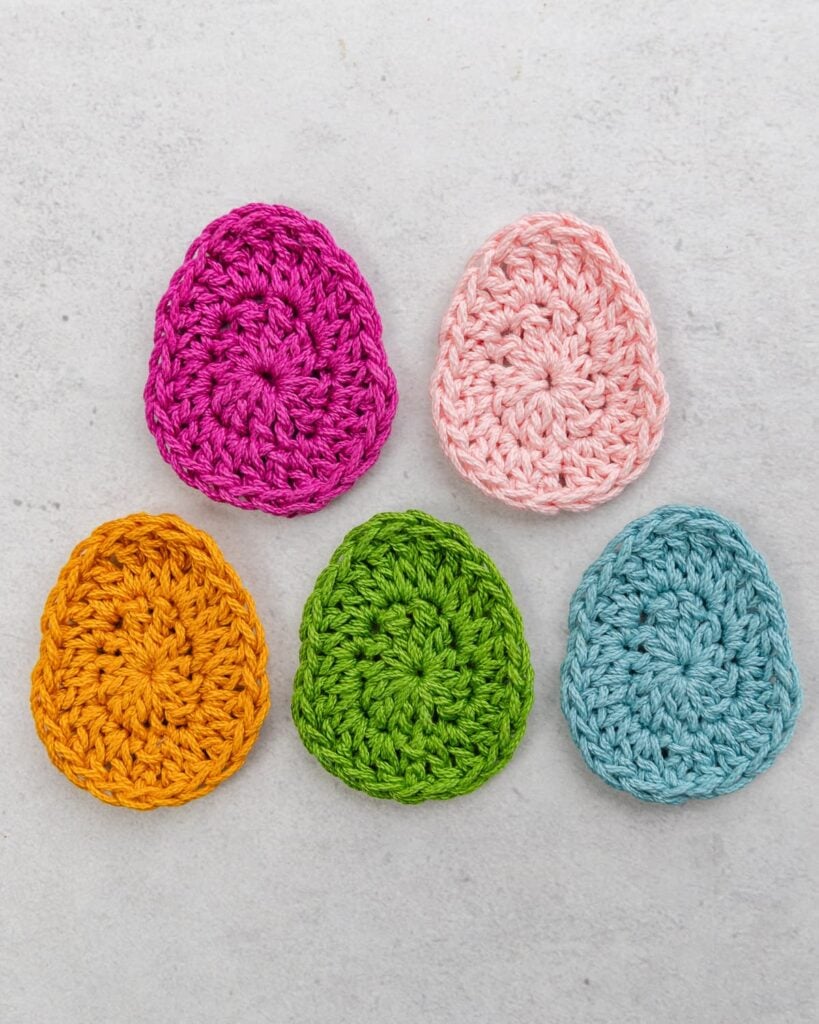 Basket filled with colorful striped and solid crochet Easter eggs in pastel pink, mint, and lemon
