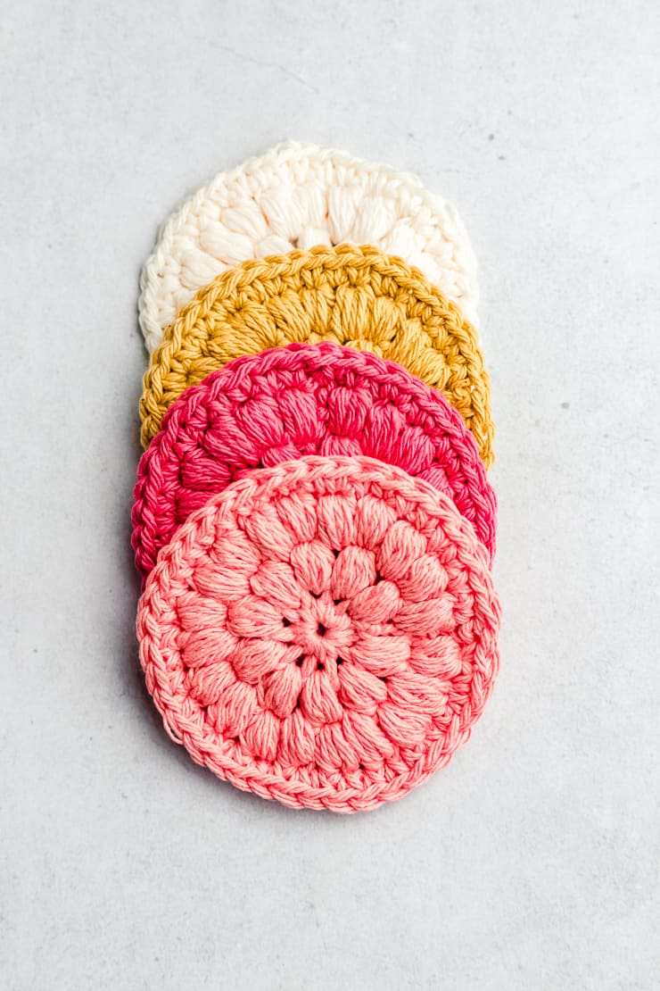 Stack of pastel pink and neutral cotton crochet face scrubbies on bathroom tray