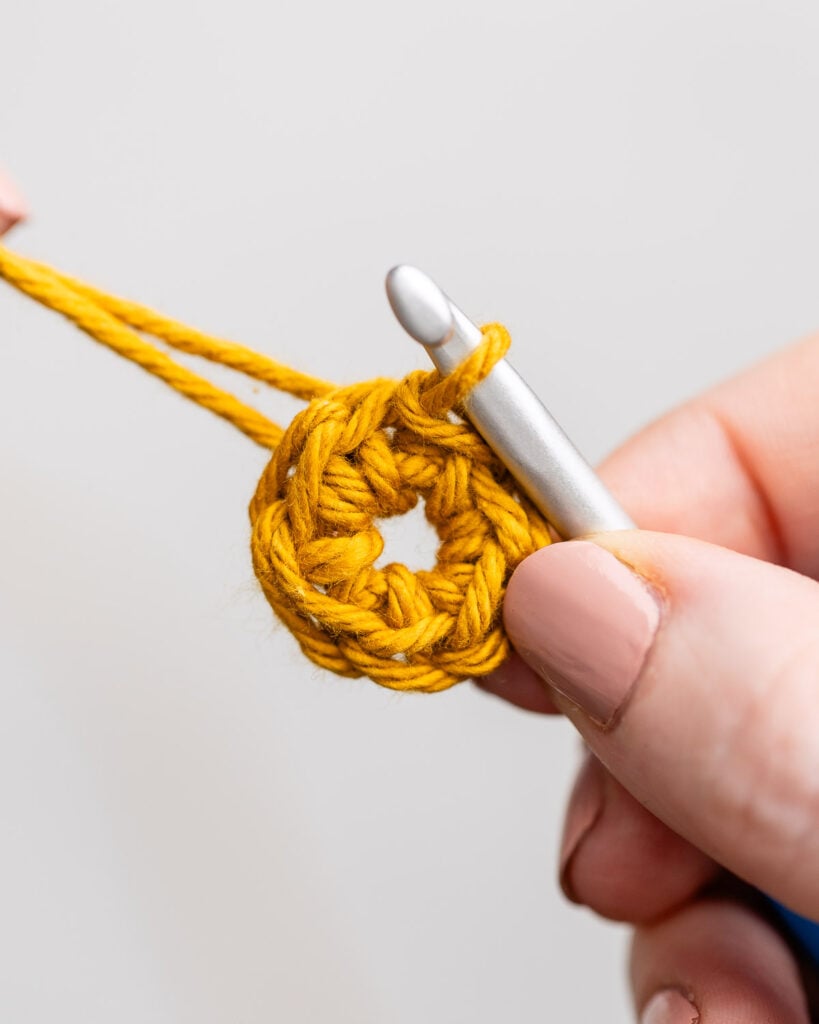 Hands wrapping yarn around fingers to create a foolproof crochet magic ring