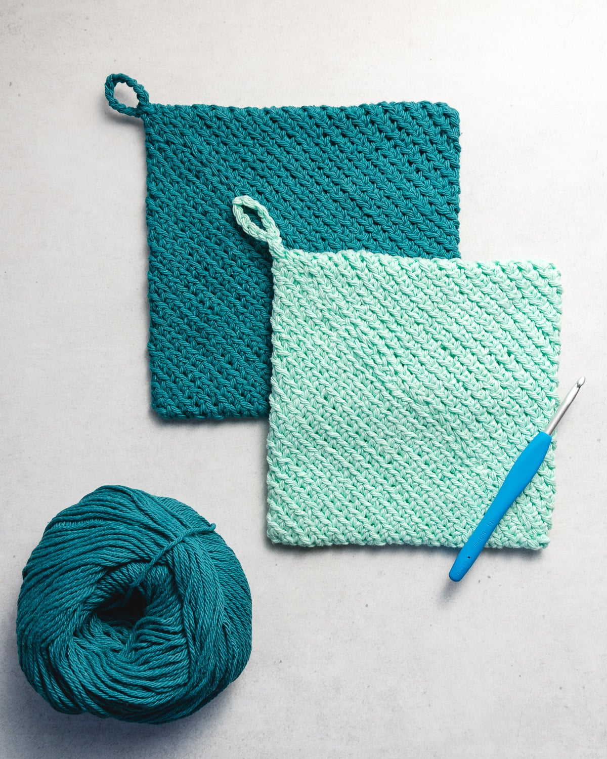 Pair of double thick crochet potholders with hanging loops on kitchen table