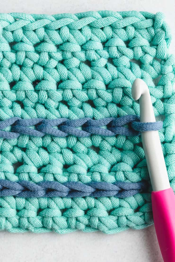 Crochet hook performing clean slip stitch join on colorful circular granny motif