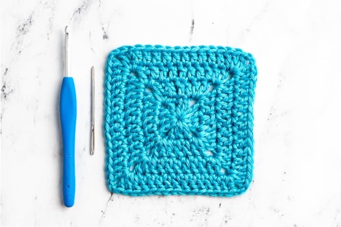 Clean modern solid crochet granny squares arranged neatly on wooden table