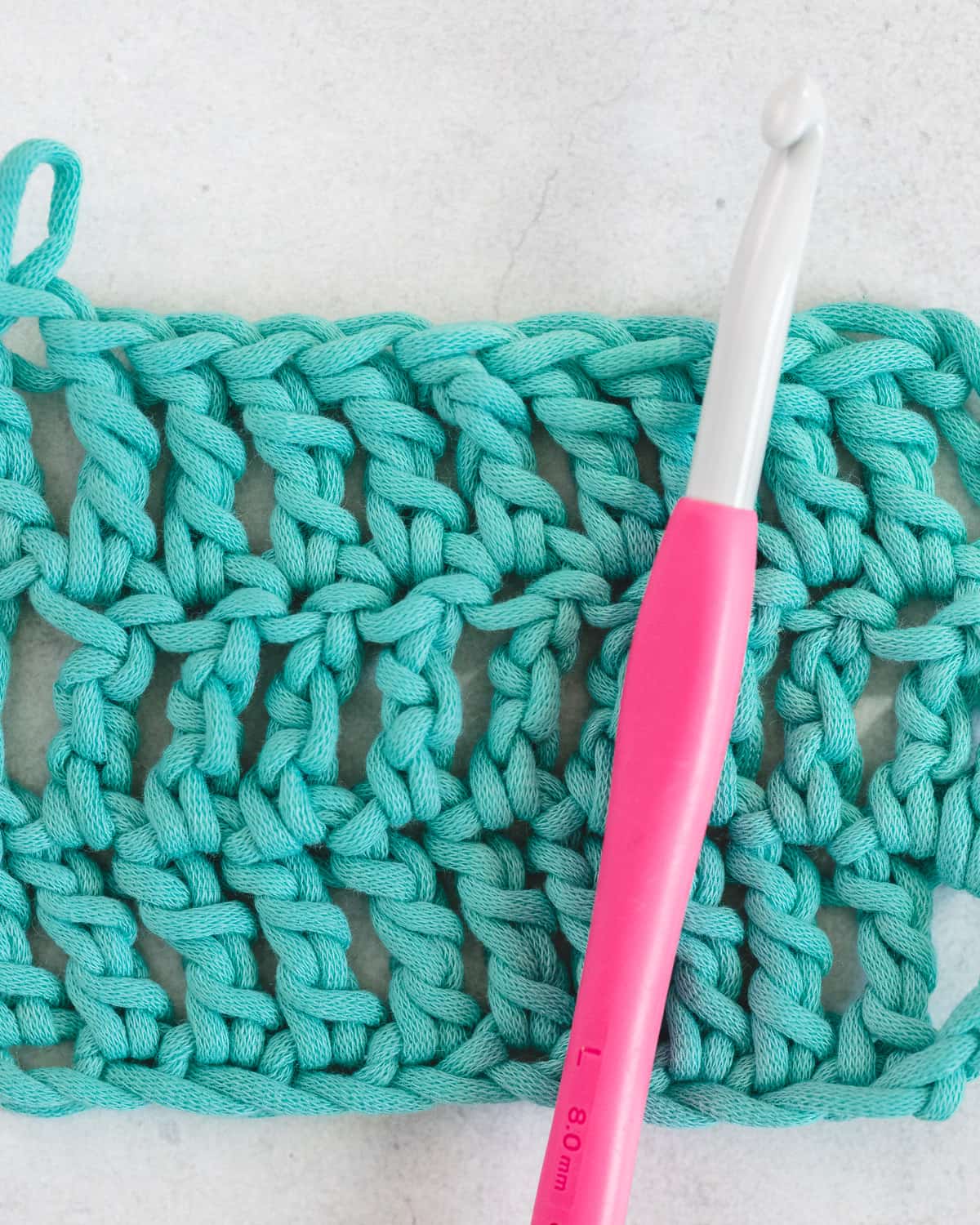 Finished treble crochet sample showcasing airy openwork lace drape on natural linen
