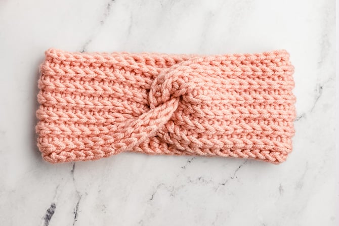 Cream textured ribbed crochet twisted ear warmer headband on wood surface