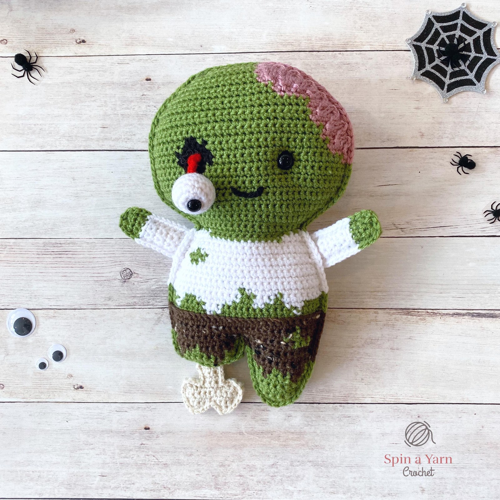 Finished creepy cute zombie amigurumi with exposed pink brain and tattered suit